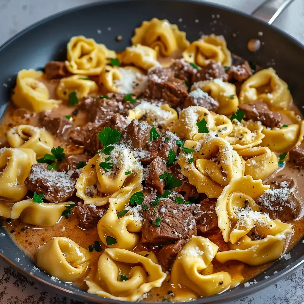 Ein cremiges Tortellini-Nudelgericht mit Bœufstückchen und Parmesan, garniert mit Petersilie.